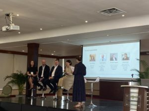 Image of panelists on a stage with a screen behind them