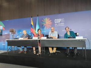  People seated around a table at a conference session at COP16.