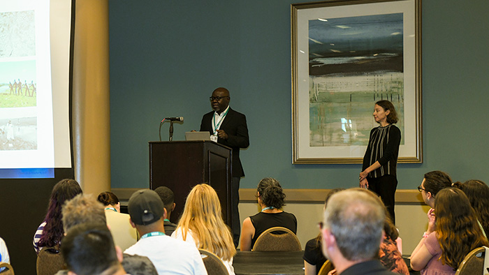 A session speaker presents before a medium-sided audience from a podium. 