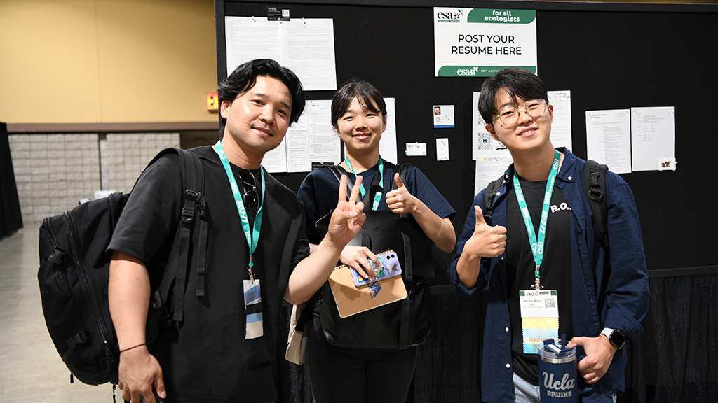 Three participants pose in front of a wall at a career center session.