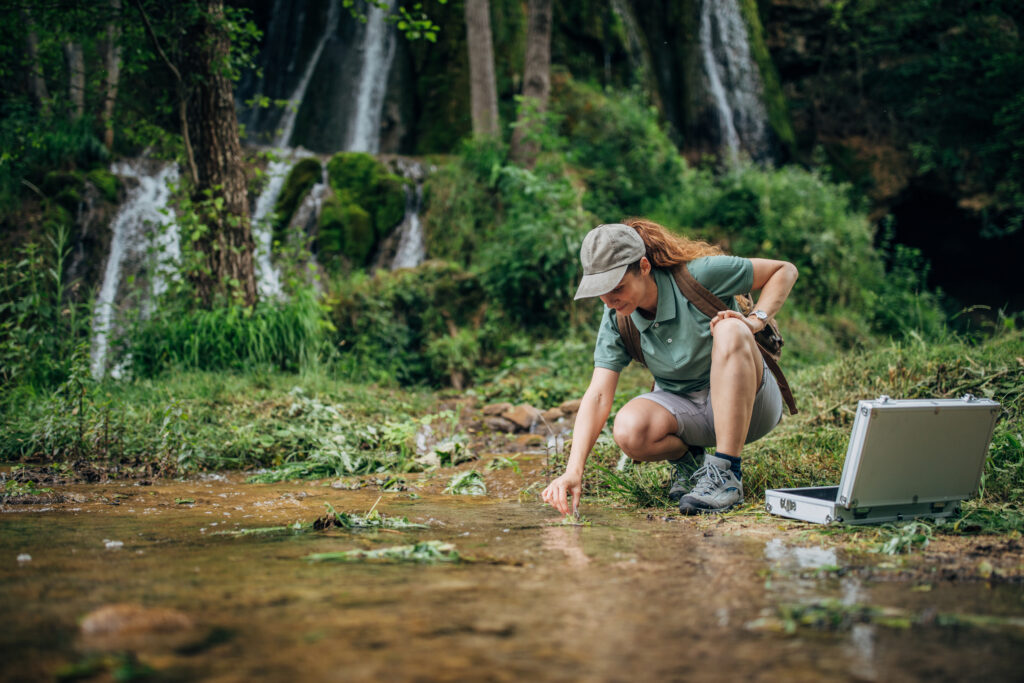 an ecologist takes a water sample in a riparian ecosystem