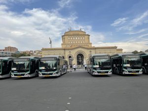 Buses lined up in front of a grand building.