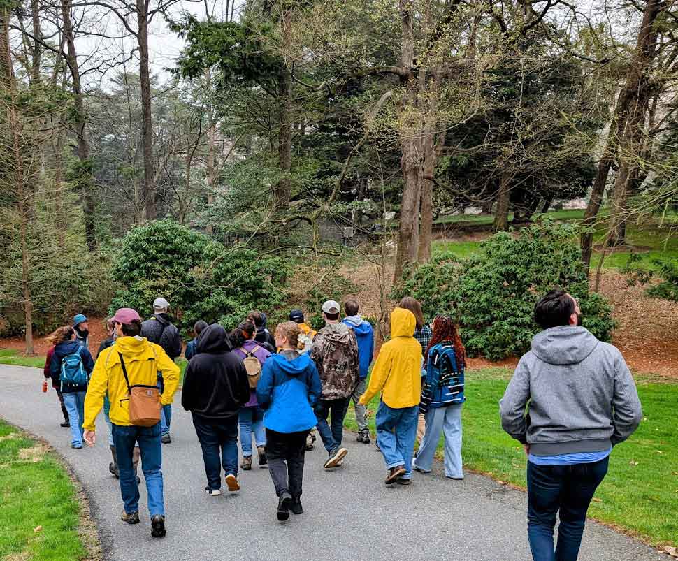 A group of meeting attendees walk down a path facing away from the camera.
