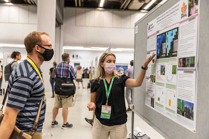A poster presenter discusses their content with an interested onlooker.
