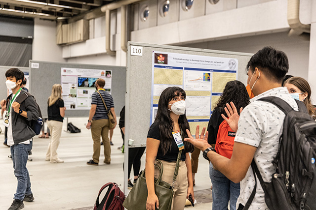 A conversation between 3 attendees at the poster session of the ESA 2022 Meeting.