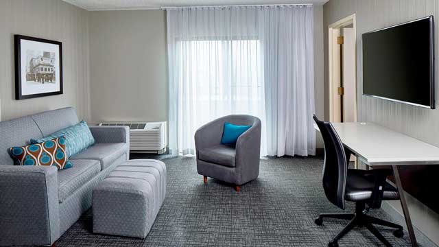 A modern hotel room with big screen and comfortable seating.