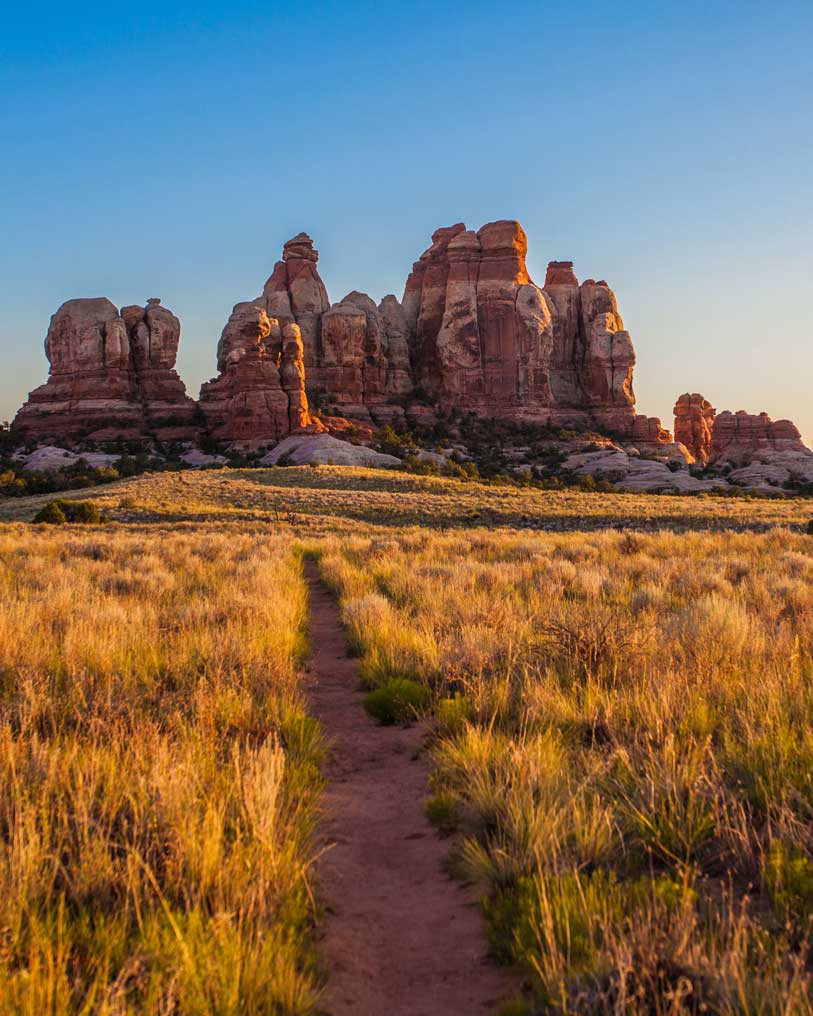 Image of a pathway through an arid desert with clay mountains in the backdrop.