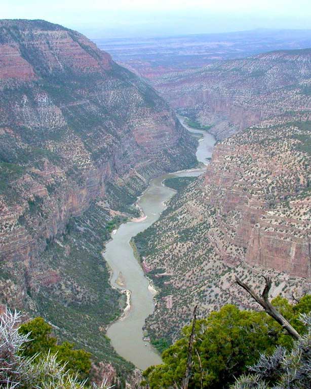 A view from atop a mountain looking down on a river flowing through a canyon. 