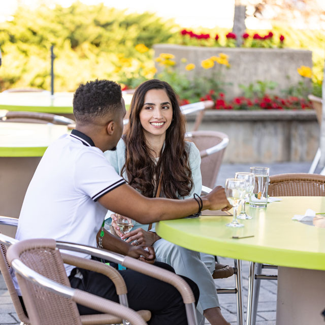 Two seated people enjoy refreshments at a social event.