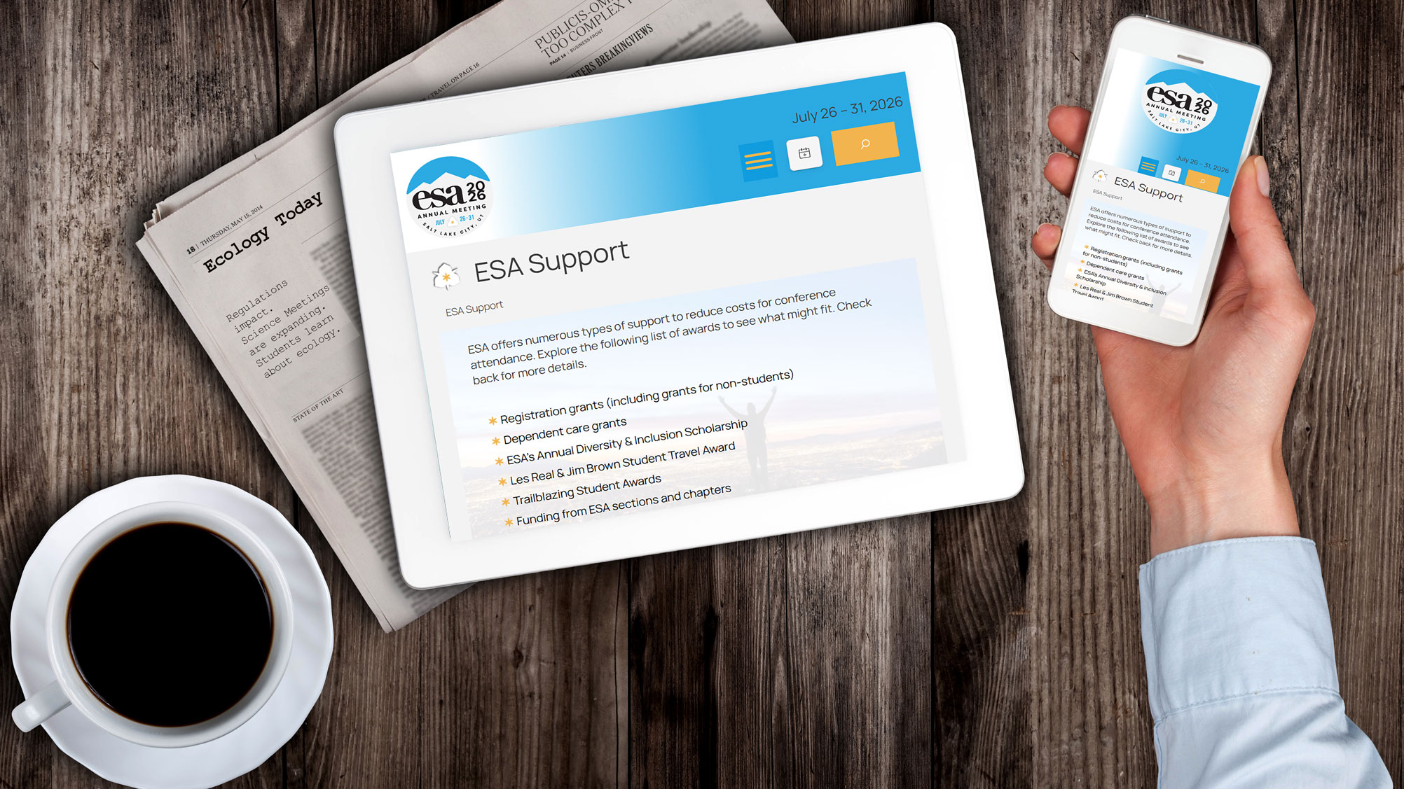 A cup of coffee sits next to a tablet and phone with the annual meeting website loaded.