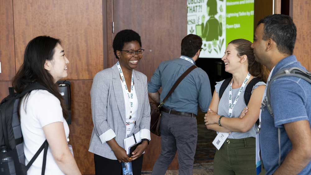 A group of four attendees laugh together.