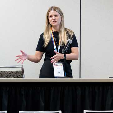 A presenter speaks in front of the audience. 