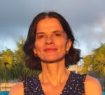 Picture of Maira Uriarte standing before an overcast, tropical backdrop.