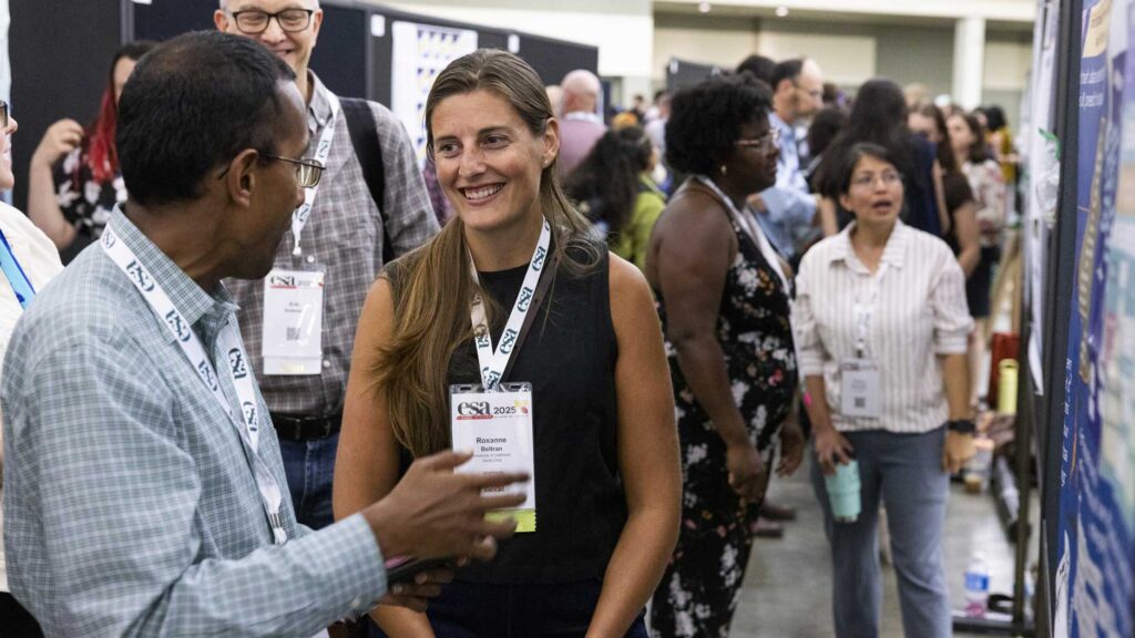 Two attendees discuss a presenters poster.
