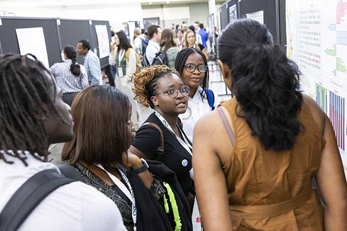 A woman quizzical asks a question of a poster presenter.