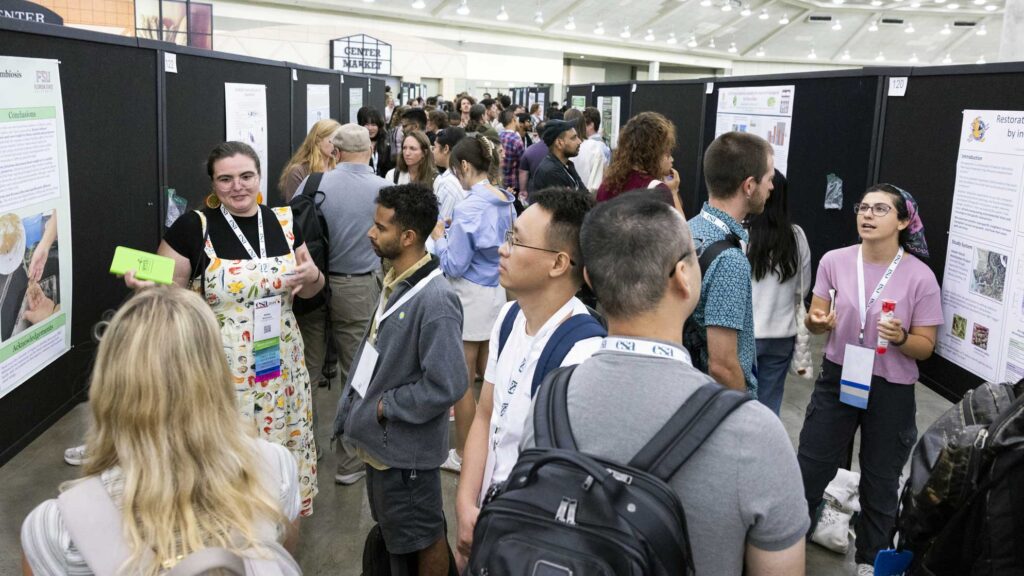 A large group is assembled and looking at poster presentations.