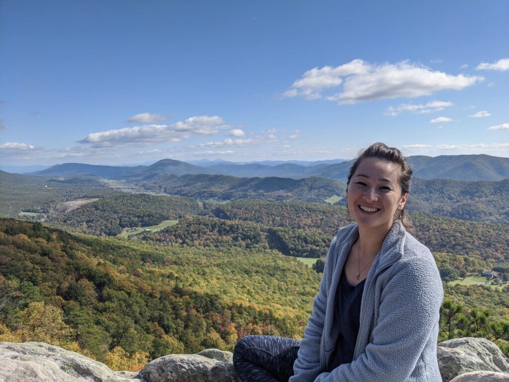 Image of Malina Loeher seated before a mountain valley. 