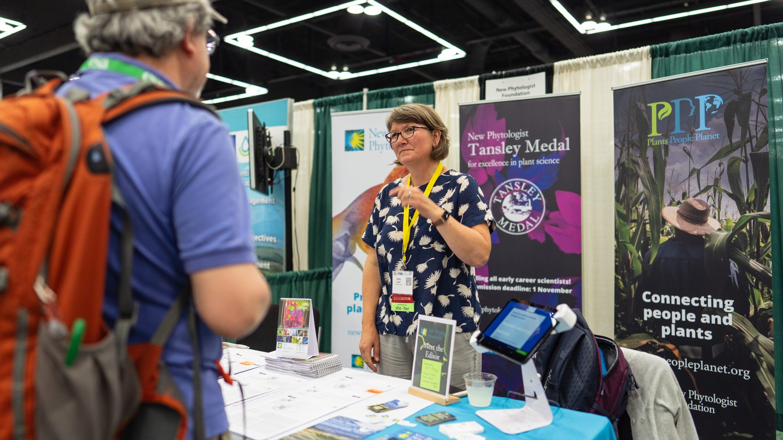 An exhibitor converses with a meeting attendee. 