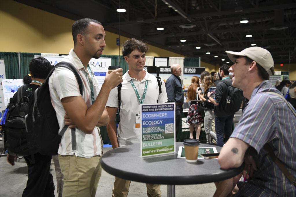 A few attendees discuss journals at a small roundtable.
