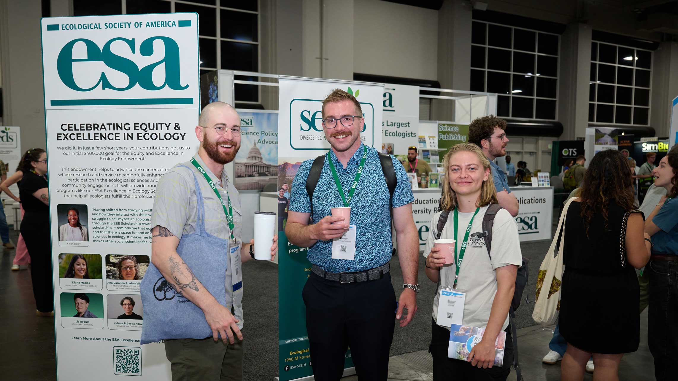 A few meeting attendees stand by the ESA booth with smiles.