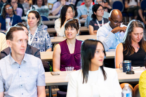 A group of seated attendees await a presentation. 