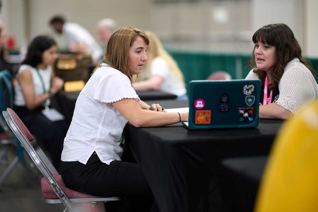 Two attendees discuss their professional paths in front of a computer. 