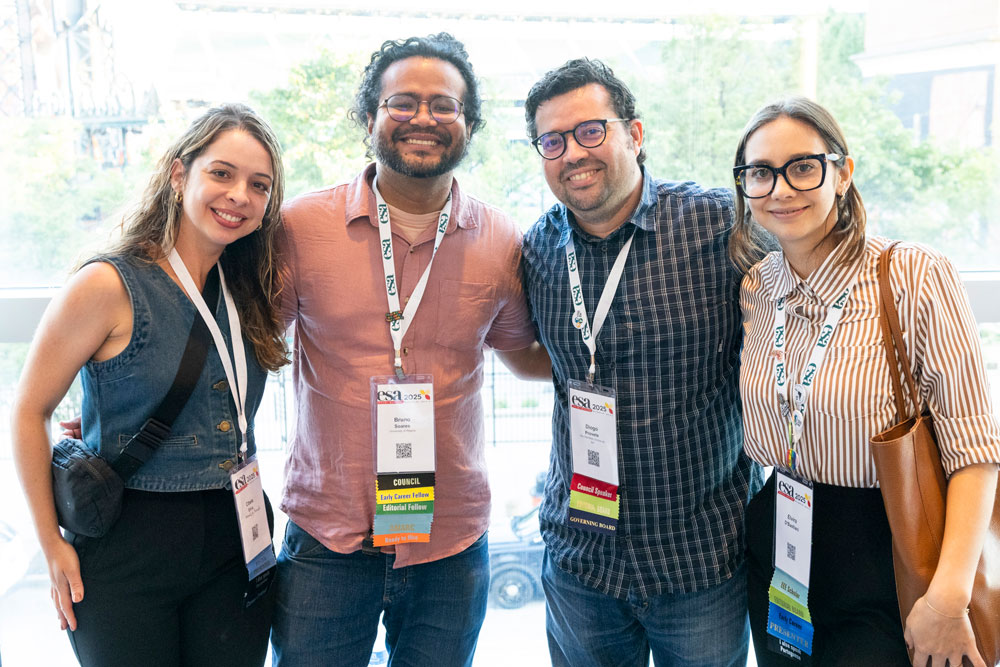 4 editors including an editorial fellow pose fore a photo arm in arm. 