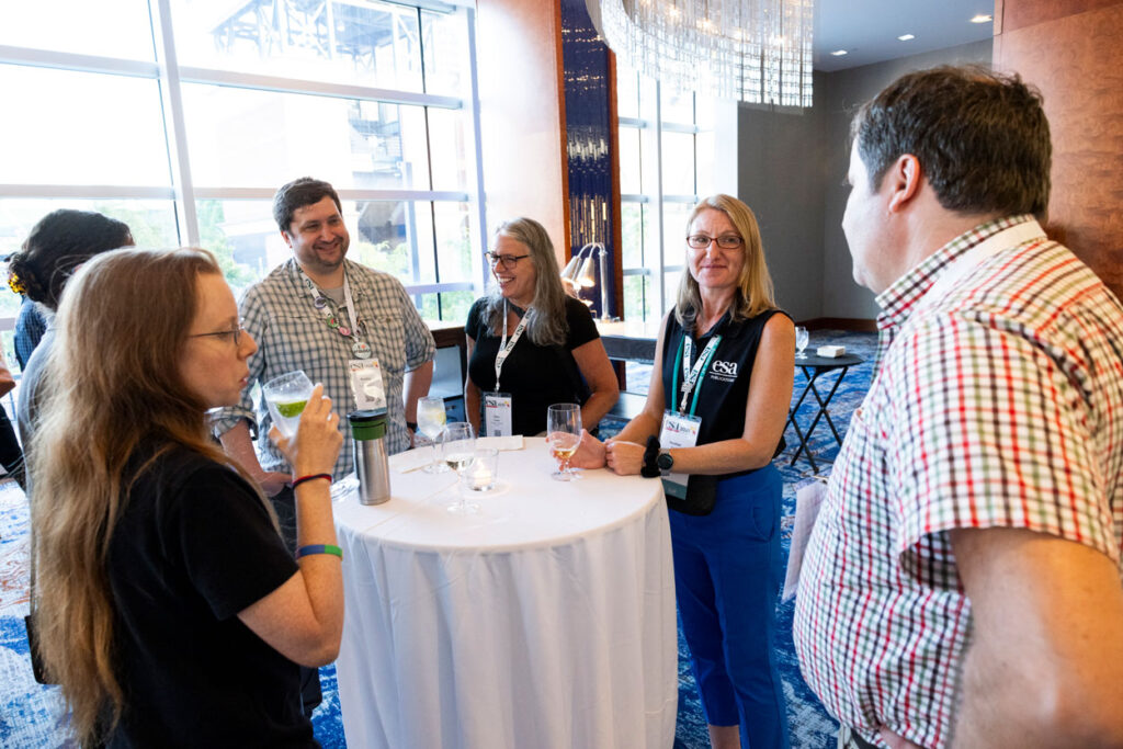 ESA Publications staff stand at a table in discussion. 