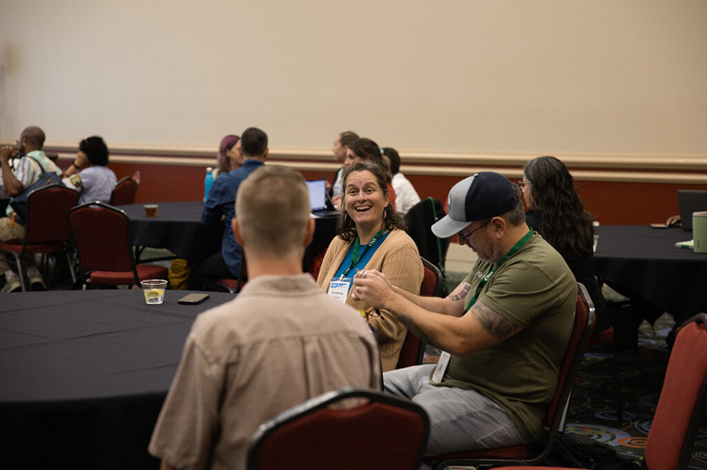A member of a round table shows her delight with raised eyebrows and a big smile.