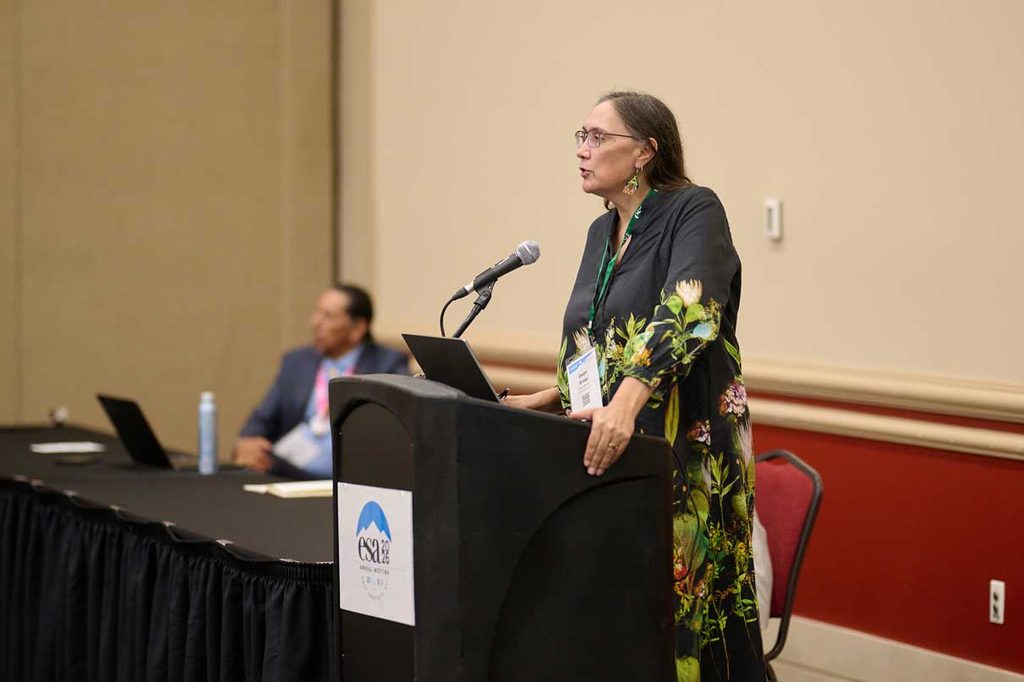 A woman presents her findings at a podium.
