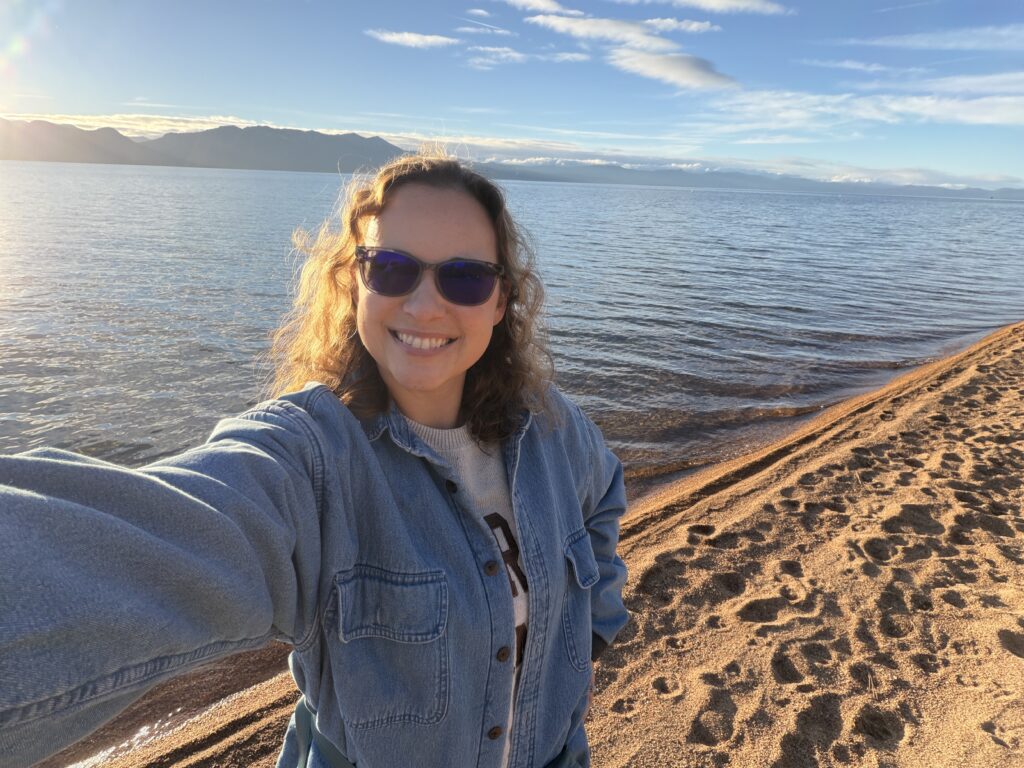 Photo of Morgan Frost with a water background and sandy beach.