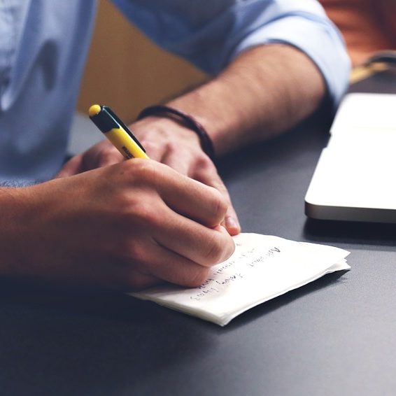 A man takes a note on a piece of paper with a pencil.