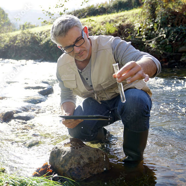 An ecologist examines a test tube of creek water.