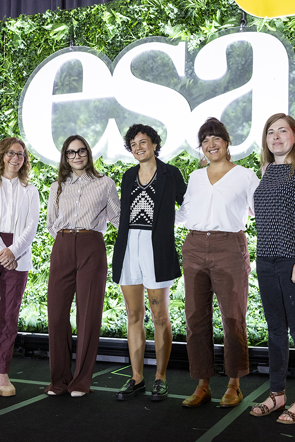 Five smiling people in front of the illuminated ESA logo.