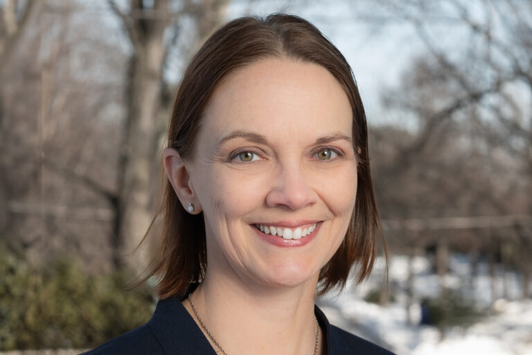 A smiling person wearing a blazer jacket