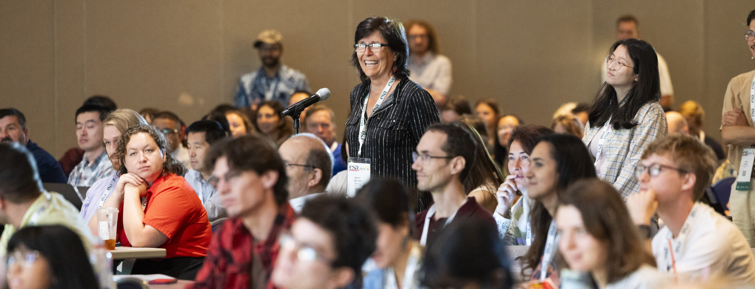 People lining up at a microphone to ask questions at a plenary during the ESA 2025 Annual Meeting